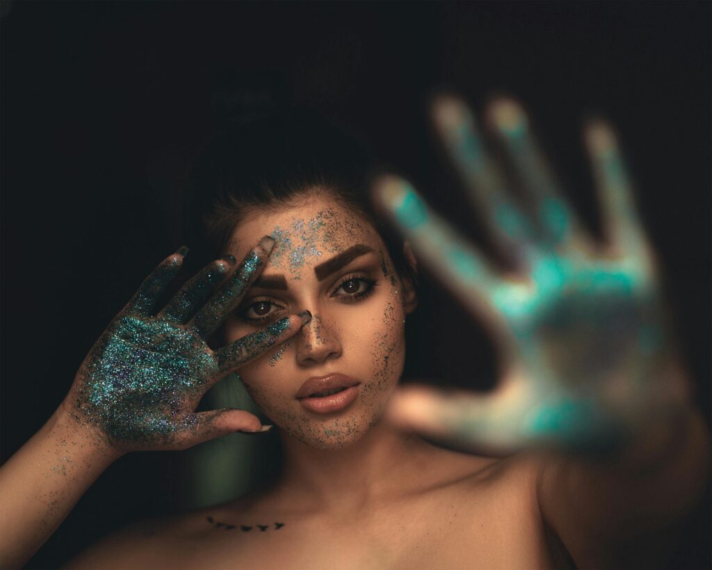 Woman with glitters on her hands and face - How Biodegradable Glitters Can Help Sparkle Sustainability